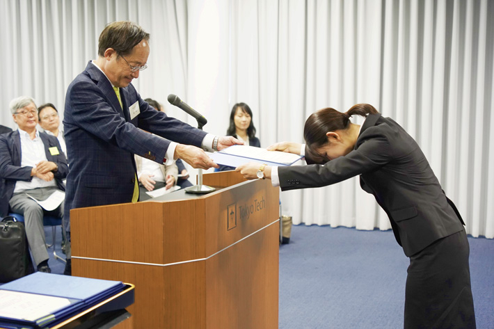 益一哉学長から奨学生証を授与される学生(右)