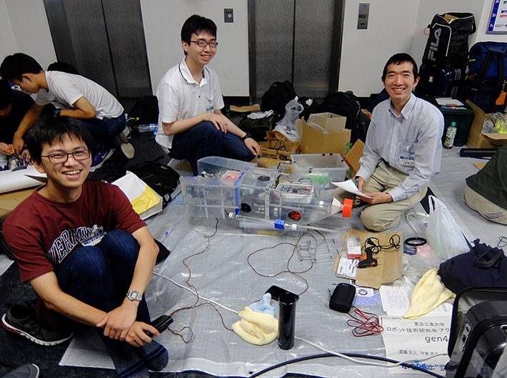 3位のアクア研gen班メンバーとメンテナンス中の機体 左手前から(時計回りに)水上さん、源元さん、斎藤さん