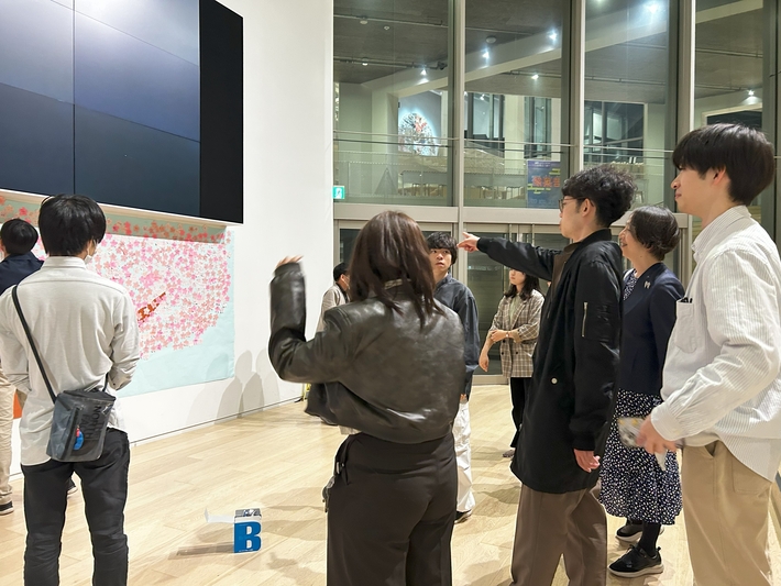 Taki Plaza 地下2階のマルチスクリーン下に桜を掲示する学生たち